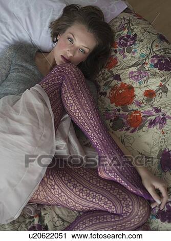Stock Image - Woman lying down on bed. Fotosearch