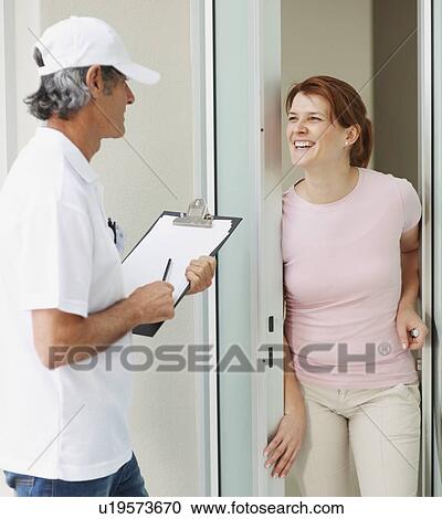 Stock Image - Woman talking to man at the door. Fotosearch