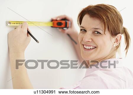 Stock Image - Woman using measuring tape. Fotosearch