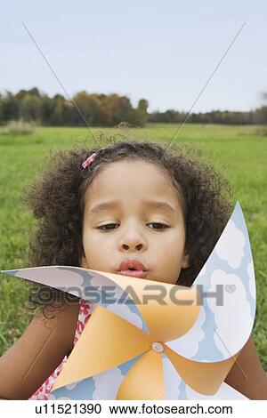 Stock Image - Young girl blowing toy windmill. Fotosearch
