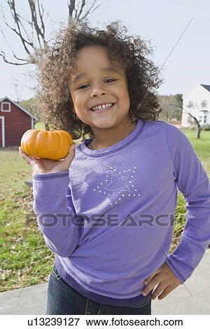 Stock Photo - Young girl holding pumpkin. Fotosearch