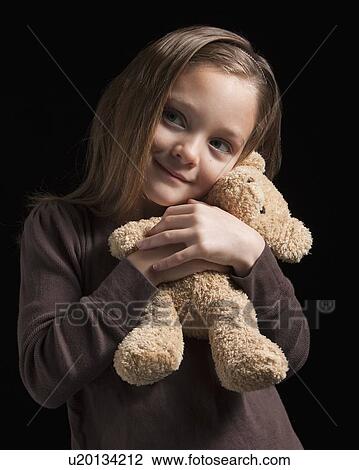 Stock Image - Young girl hugging teddy bear. Fotosearch