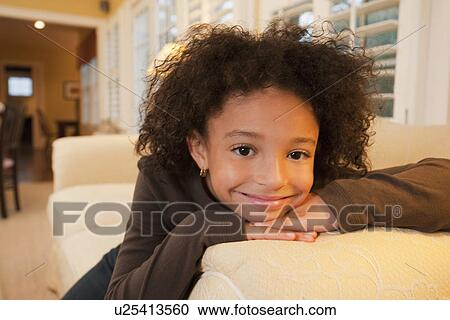 Stock Image - Young girl on couch. Fotosearch