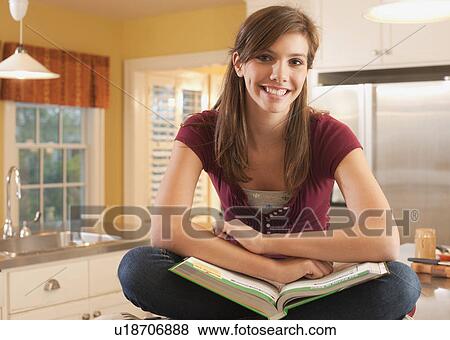 Stock Photo - Young girl sitting on kitchen counter. Fotosearch