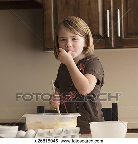 Stock Photography - Young girl tasting cookie batter. Fotosearch
