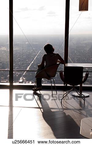 Stock Image - Woman sitting by window at Chicago, John Hancock Centre. Fotosearch