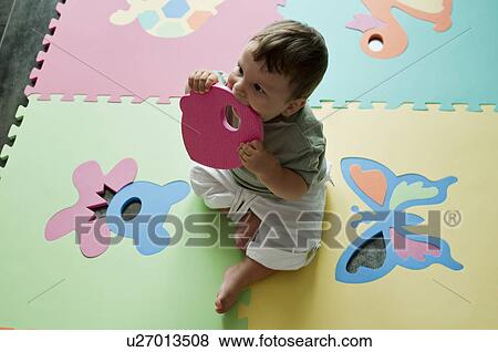 Stock Photo - Baby boy chewing on play mat. Fotosearch