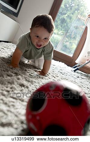 Stock Photo - Baby boy crawling toward ball. Fotosearch