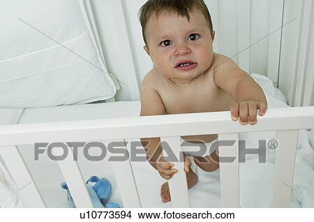 Picture - Baby boy in crib upset. Fotosearch