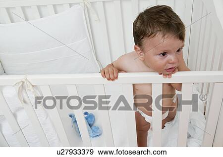 Stock Photo - Baby boy in crib upset. Fotosearch