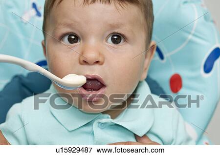 Baby boy in high chair with spoon at his mouth View Large Photo Image Stock Photo - Baby boy in high chair with spoon at his mouth. Fotosearch
