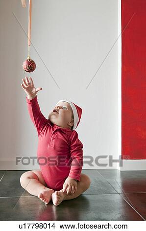 Baby boy sitting on floor reaching for Christmas ball View Large Photo Image Picture - Baby boy sitting on floor reaching for Christmas ball. Fotosearch