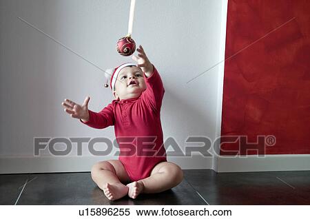 Baby boy sitting on floor reaching for Christmas ball View Large Photo Image Stock Photography - Baby boy sitting on floor reaching for Christmas ball. Fotosearch
