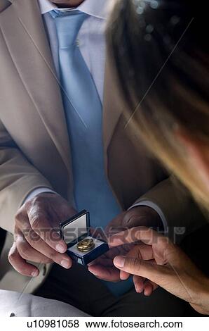 Stock Photo - Closeup of hands of young man giving a ring to young woman. Fotosearch