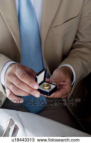 Closeup of hands of young man holding a ring in an open jewelry box View Large Photo Image Stock Image - Closeup of hands of young man holding a ring in an open jewelry box. Fotosearch