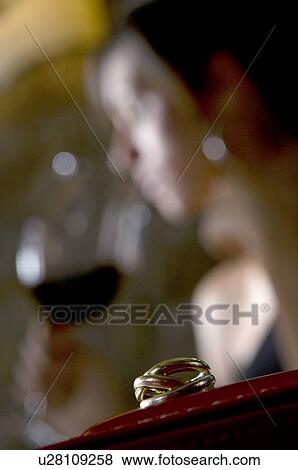 Stock Photo - Closeup of ring with young woman in the background drinking red wine. Fotosearch