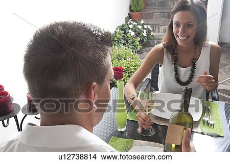 Picture - Couple at restaurant table with white wine. Fotosearch