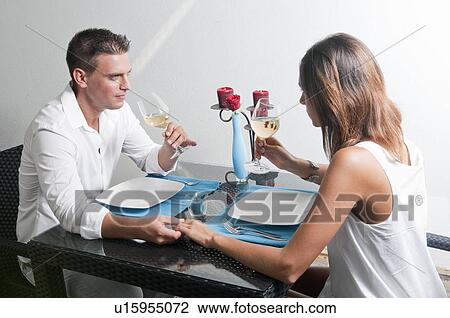 Couple sitting at table drinking white wine View Large Photo Image Stock Image - Couple sitting at table drinking white wine. Fotosearch