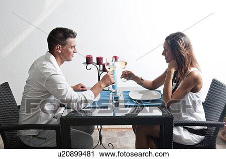 Stock Image - Couple sitting at table drinking white wine. Fotosearch