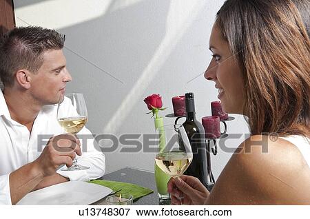 Stock Photo - Couple sitting at table drinking white wine. Fotosearch