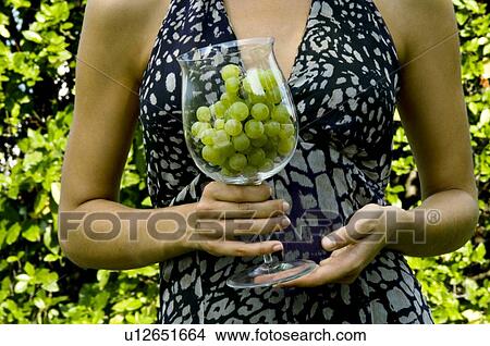 Picture - Torso of young woman in vineyard with a wineglass of white grapes. Fotosearch