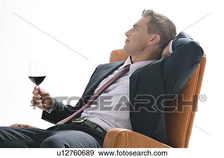 Stock Photo - Young man in business suit sitting with glass of red wine. Fotosearch