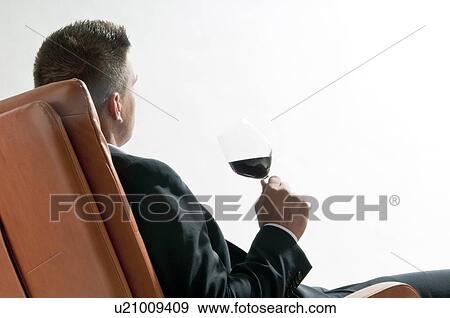 Young man in business suit sitting with glass of red wine View Large Photo Image Stock Photo - Young man in business suit sitting with glass of red wine. Fotosearch