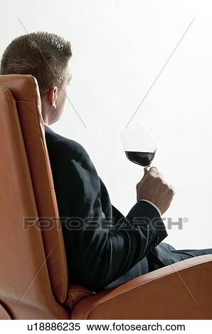 Young man in business suit sitting with glass of red wine View Large Photo Image Stock Photography - Young man in business suit sitting with glass of red wine. Fotosearch