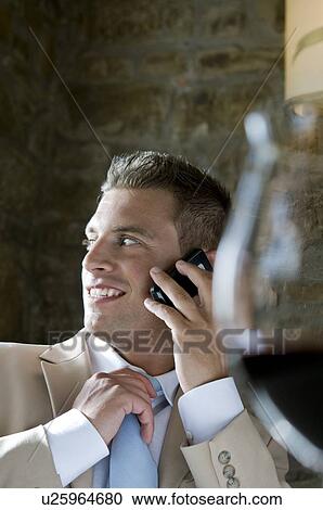 Young man in suit sitting with mobile phone at a restaurant View Large Photo Image Stock Image - Young man in suit sitting with mobile phone at a restaurant. Fotosearch
