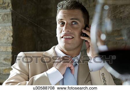 Stock Photo - Young man in suit sitting with mobile phone at a restaurant. Fotosearch