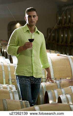 Stock Photo - Young man in wine cellar with glass of red wine. Fotosearch