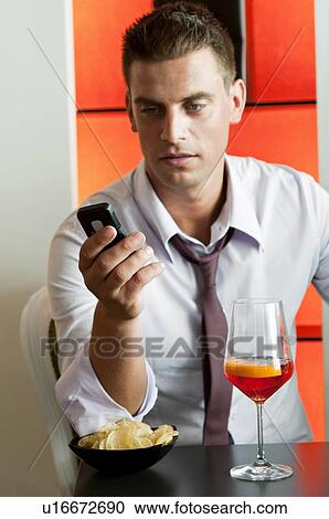 Young man sitting with a glass of orange wine and mobile phone View Large Photo Image Stock Image - Young man sitting with a glass of orange wine and mobile phone. Fotosearch