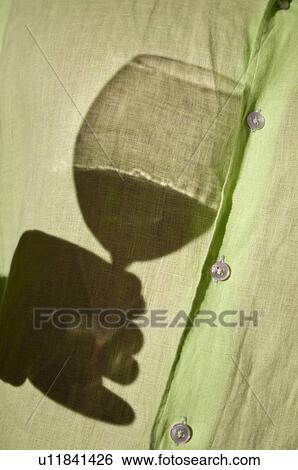 Stock Photograph - Young man's torso with shadow of hand holding wine glass. Fotosearch