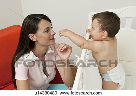 Young woman on arm chair and baby boy in crib View Large Photo Image Stock Image - Young woman on arm chair and baby boy in crib. Fotosearch