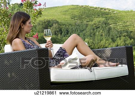Young woman sitting on couch in vineyard with white wine reading a book View Large Photo Image Stock Image - Young woman sitting on couch in vineyard with white wine reading a book. Fotosearch