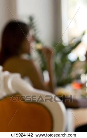 Young woman sitting with a glass of orange wine eating potato chips View Large Photo Image Stock Image - Young woman sitting with a glass of orange wine eating potato chips. Fotosearch
