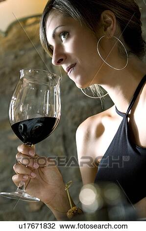 Stock Image - Young woman with a glass of red wine at restaurant. Fotosearch