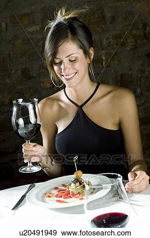 Stock Photo - Young woman with plate of food and wine at restaurant. Fotosearch