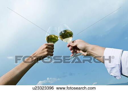 Young woman's and young man's hands holding wineglasses with white wine and toasting View Large Photo Image Stock Photograph - Young woman's and young man's hands holding wineglasses with white wine and toasting. Fotosearch