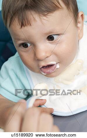 Stock Image - Young woman's hand feeding baby boy. Fotosearch