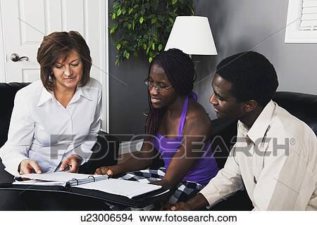 a businesswoman showing a document to a couple View Large Photo Image Picture - a businesswoman showing a document to a couple. Fotosearch