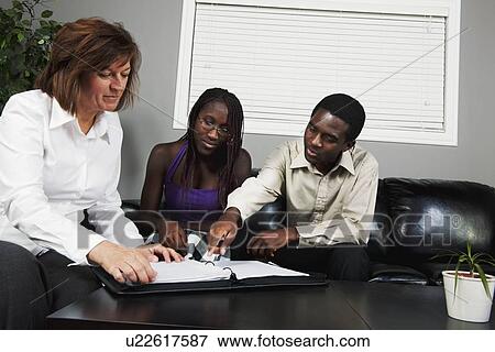 Stock Photo - a businesswoman showing a document to a couple. Fotosearch