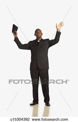 a man wearing a clerical collar and holding his bible up with hands raised and looking up View Large Photo Image Stock Image - a man wearing a clerical collar and holding his bible up with hands raised and looking up. Fotosearch