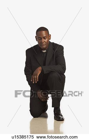 Stock Photography - a man wearing a clerical collar kneeling in prayer. Fotosearch