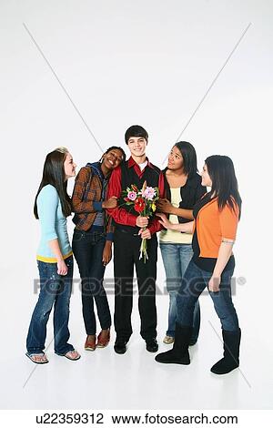 Stock Image - girls surrounding a boy who is holding flowers. Fotosearch