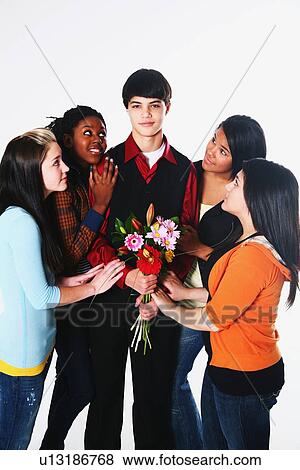 Stock Photo - girls surrounding a boy who is holding flowers. Fotosearch