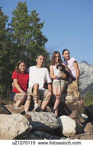 Stock Photography - kananaskis country, alberta, canada; a family sitting on the rocks in the mountains with their dog. Fotosearch