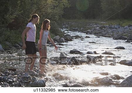 Stock Photography - kananaskis country, alberta, canada; two girls throwing rocks into the river. Fotosearch