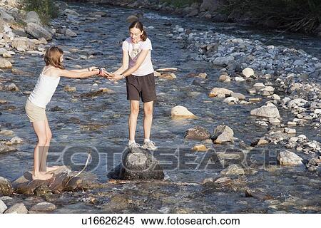 Stock Photography - kananaskis country, alberta, canada; two girls playing on the rocks in the river. Fotosearch