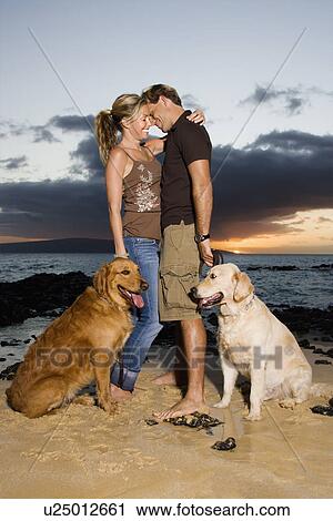 Stock Image - Affectionate Couple With Dogs at the Beach. Fotosearch